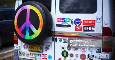 Santa Fe, NM: A van decorated with a peace sign and covered with progressive political bumper stickers (as well as others) parked off a road in downtown Santa Fe.